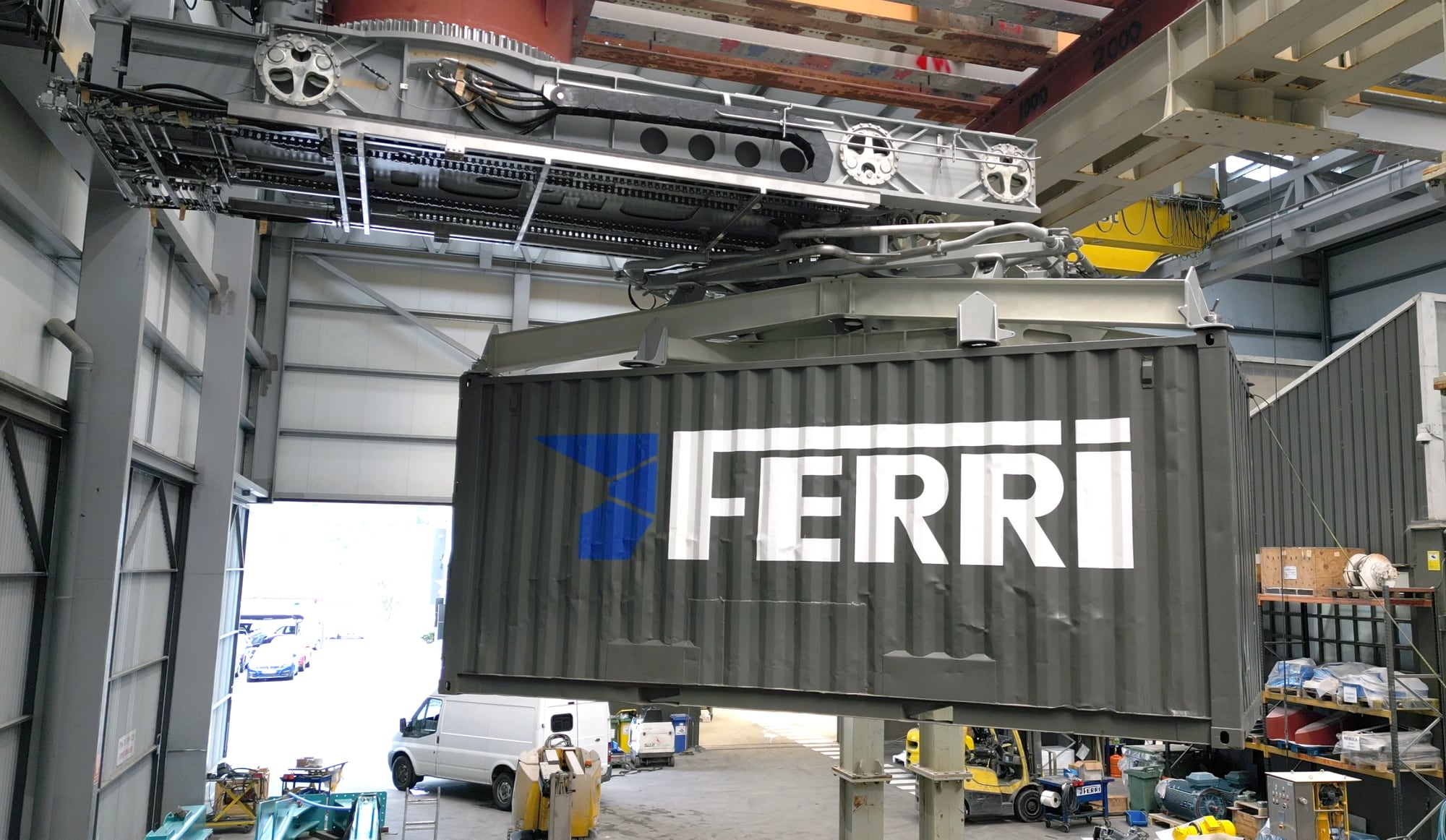 Contenedor con el logotipo de FERRI suspendido de un sistema de manipulación en un taller